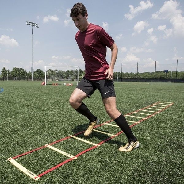 Fußballspieler absolviert Koordinationsübung über eine Trainingsleiter