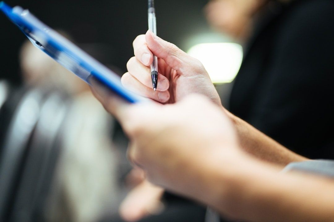 Hände mit Stift und Klemmbrett bei einer handschriftlichen Notiz