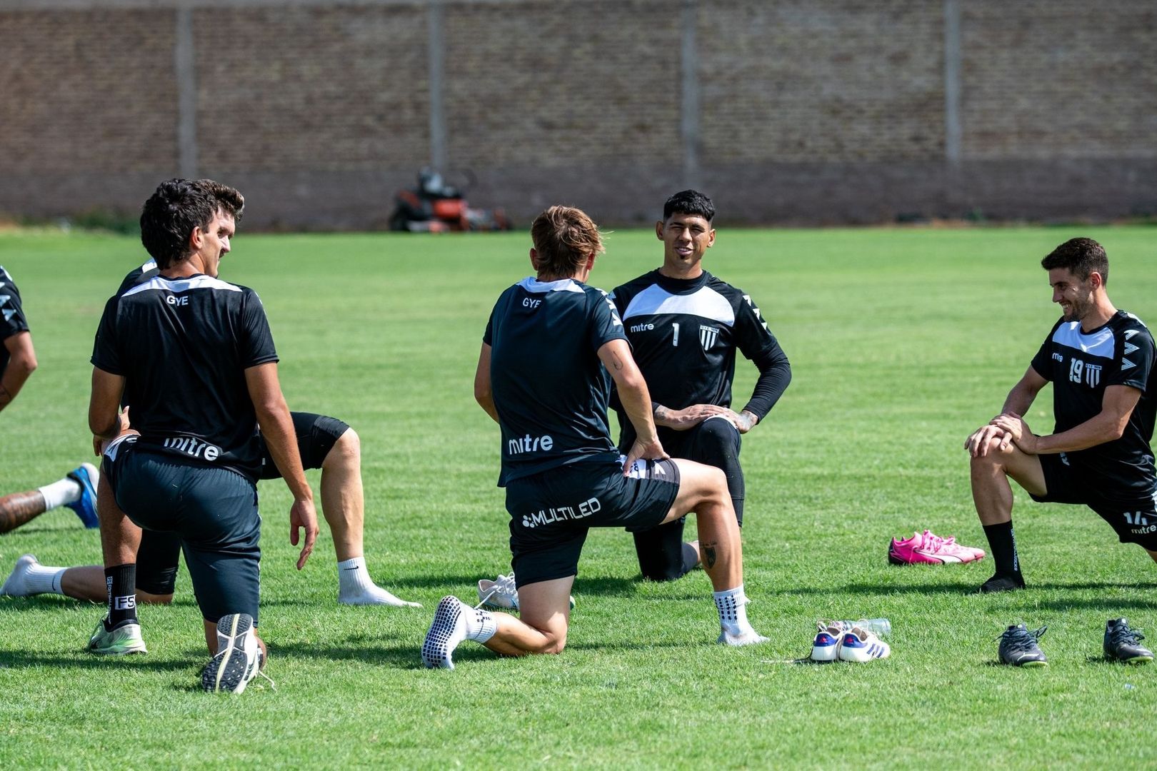 Fußballspieler absolvieren gemeinsam Dehnübungen auf einem Rasenplatz