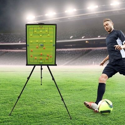 Fußballer neben Taktiktafel auf einem beleuchteten Spielfeld